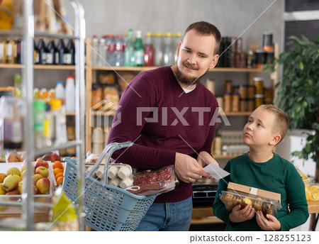 Young man with son buying groceries from shopping list Young man with son buying groceries from shopping list 128255123