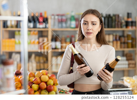 Young woman choosing beer in grocery store Young woman choosing beer in grocery store 128255124