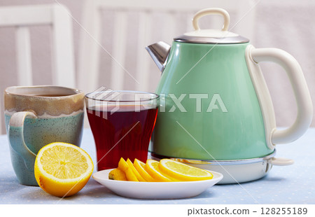 Electric kettle, two cups with tea and sliced lemon Electric kettle, two cups with tea and sliced lemon 128255189