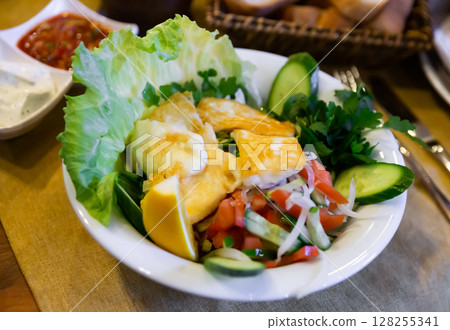 Fried halloumi cheese with salad of vegetables, greens and lemon Fried halloumi cheese with salad of vegetables, greens and lemon 128255341