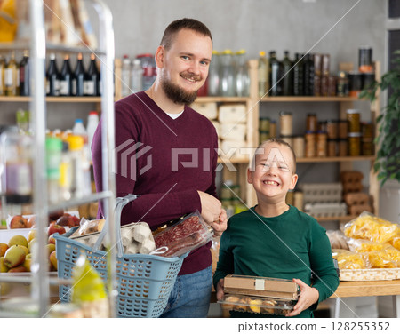 Man and his son choose groceries in a supermarket Man and his son choose groceries in a supermarket 128255352