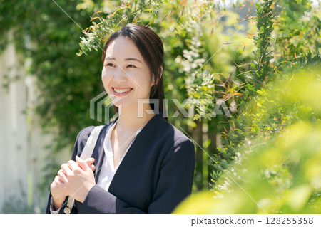 一位身穿西裝的女士站在白牆前 128255358