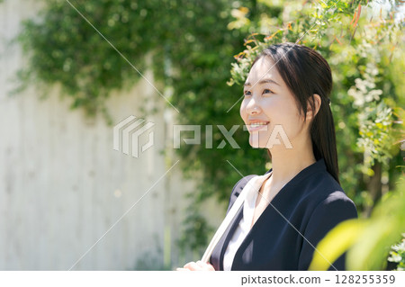 一位身穿西裝的女士站在白牆前 一位身穿西裝的女士站在白牆前 128255359