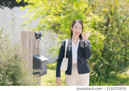 一名女子站在房屋銘牌前 一名女子站在房屋銘牌前 128255859