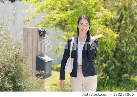 A woman standing in front of a house nameplate 128255860