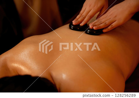 Hot stone massage at spa salon in luxury resort with warm candle light.Quiescent 128256289