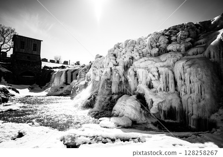 Sioux Falls Park waterfall with ice and snow. Cascading snowmelt water pouring over the top into a pool of standing water. 128258267