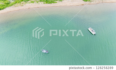 overhead view of a boat and pontoon fishing along the shore of a river. overhead view of a boat and pontoon fishing along the shore of a river. 128258289