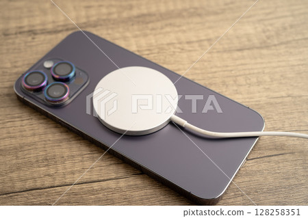 Bangkok, Thailand, January 10, 2024 Wireless charger on mobile phone, magnetic charging modern equipment of mobile phone. 128258351