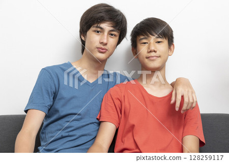 Happy teenage boys sit on sofa, watch comic TV show. Teen boy relaxing at home. Best friends lifestyle. Happy teenage boys sit on sofa, watch comic TV show. Teen boy relaxing at home. Best friends lifestyle. 128259117