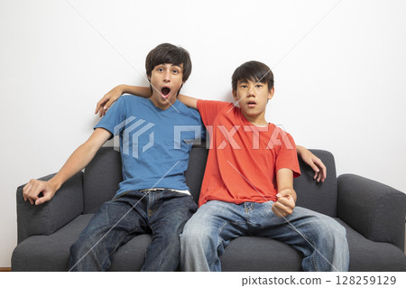 teen boys watching television at home in living room, watching football match at home. teen boys watching television at home in living room, watching football match at home. 128259129