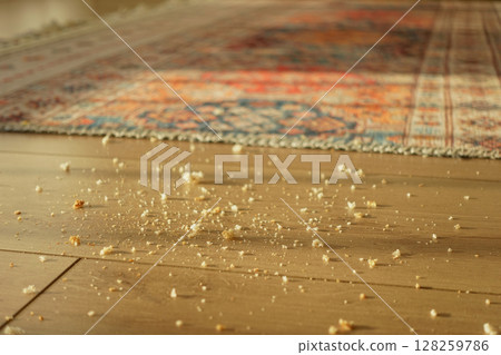 Crumbs lie scattered on a wooden floor, dirty floor concept  128259786