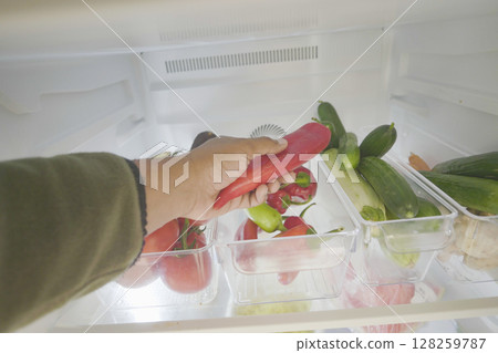 Fresh vegetables in refrigerator with hand selecting peppers 128259787