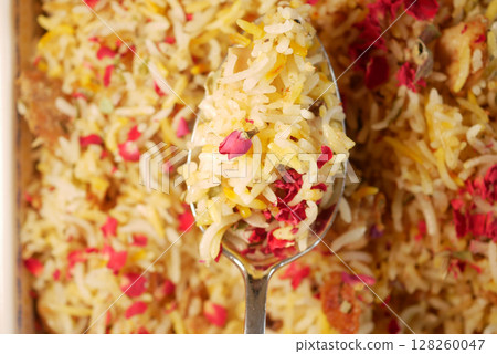 Colorful biryani served in a large spoon with rose petals Colorful biryani served in a large spoon with rose petals 128260047