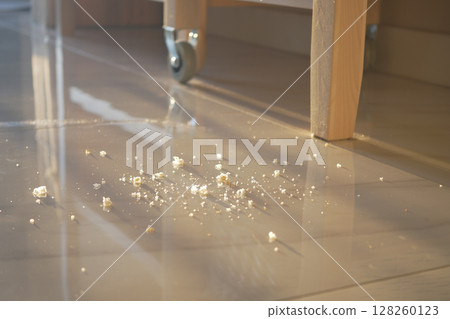Crumbs scattered on shiny floor near wooden furniture 128260123