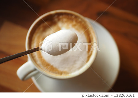 Enjoying a warm cup of coffee with sugar on a spoon 128260161