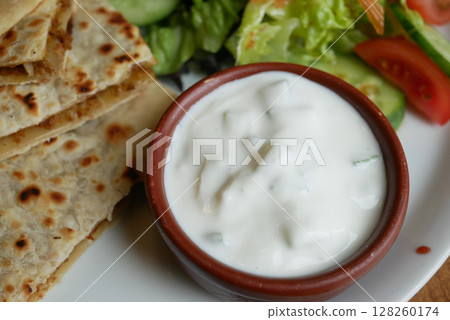 Delicious flatbread with yogurt dip and fresh salad 128260174