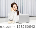 穿著工作服的女人接電話並在電腦上工作 02 128260642