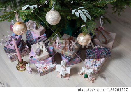 Vibrant pink and purple gift boxes with shiny ribbons rest under a Christmas tree adorned with glowing lights, creating a playful and joyful festive scene 128261507