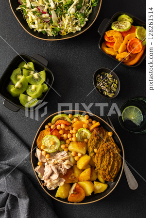 Enjoy a nutritious breakfast with baked sweet potato, carrots, zucchini, chicken breast, and lentil cutlets, complemented by a fresh salad and kiwi for dessert 128261514