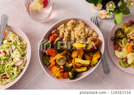 A hearty breakfast features quinoa, baked sweet potato with carrots and zucchini, broccoli, beans, and turmeric chicken, alongside a fresh salad on a sunny morning 128261516