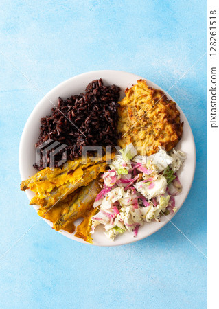 A wholesome and savory breakfast with brown rice and baked white fish, complemented by zucchini-carrot pancakes and a fresh Chinese cabbage salad with radish 128261518