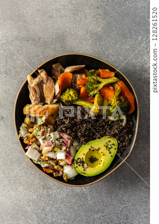 A balanced breakfast bowl with black quinoa, avocado, roast chicken, and sweet potatoes, topped with a fresh cabbage and radish salad 128261520