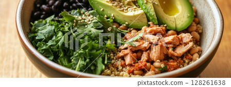 A vibrant breakfast bowl showcases quinoa, black beans, sliced avocado, chopped cilantro, and sesame seeds. A colorful and healthy way to kick off the morning 128261638