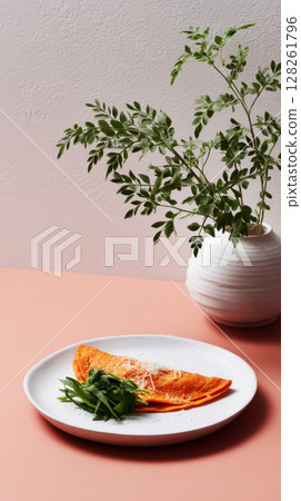 A delicious seasonal breakfast showcases a golden omelet served with fresh greens, accompanied by simple tableware and an earthy vase with foliage 128261796