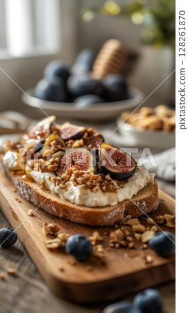 Freshly prepared toasts feature creamy cheese topped with sliced figs and chopped nuts, creating an appetizing dish on a rustic wooden table illuminated by soft sunlight Freshly prepared toasts feature creamy cheese topped with sliced figs and chopped nuts, creating an appetizing dish on a rustic wooden table illuminated by soft sunlight 128261870