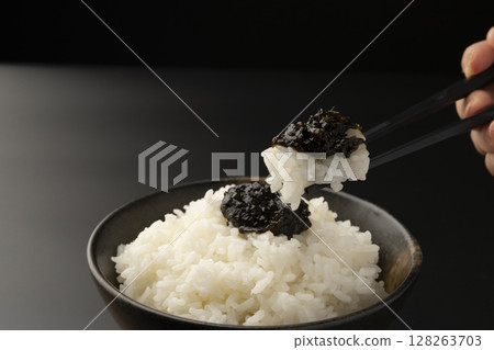 用筷子夾起鋪著海苔佃煮的米飯 用筷子夾起鋪著海苔佃煮的米飯 128263703