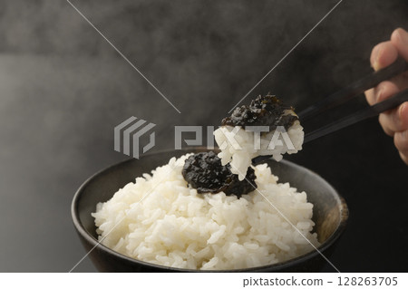 用筷子夾起鋪著海苔佃煮的米飯 128263705