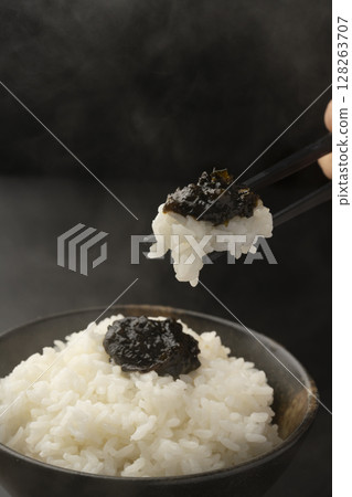 用筷子夾起鋪著海苔佃煮的米飯 128263707
