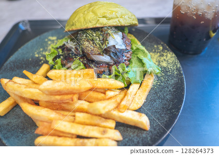 Gourmet burger with fries and a drink on a stylish plate. Gourmet burger with fries and a drink on a stylish plate. 128264373