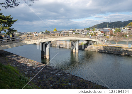 Bridge over a river with cloudy sky and scenic surroundings. 128264394