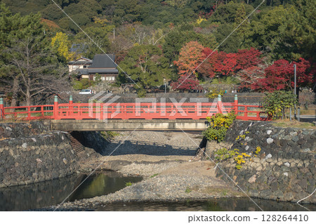 Kisen Bridge, Uji, Kyoto, Japan surrounded by vibrant foliage and calm water. 128264410