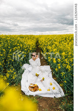 Enjoying a picnic in a vibrant yellow flower field on a cloudy day 128264448