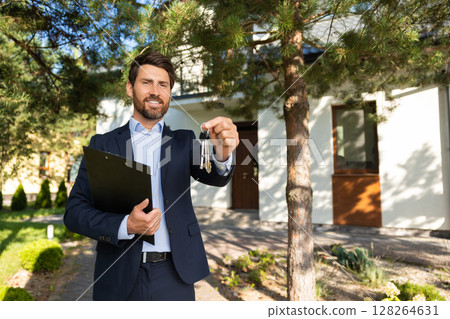 Positive real estate agent holding a key from a new house 128264631