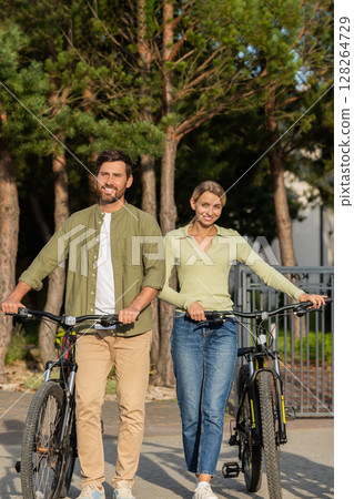 Couple preparing for bike ride outside modern house with garage Couple preparing for bike ride outside modern house with garage 128264729
