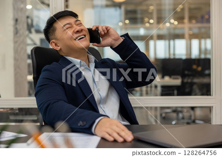 Young manager talking on the phone and feeling joyful and contented Young manager talking on the phone and feeling joyful and contented 128264756