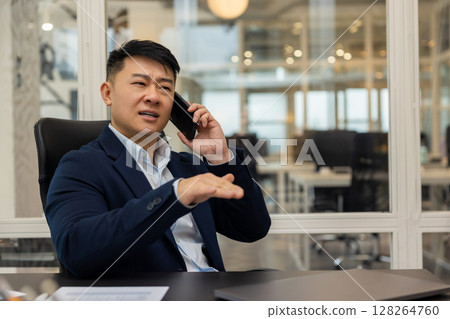 Asian young manager having a phone call and looking busy and involved 128264760