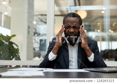 African american businessman having a headache after a busy working day 128265323