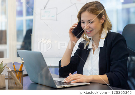 Blonde business woman working in the office and having a phone call Blonde business woman working in the office and having a phone call 128265345