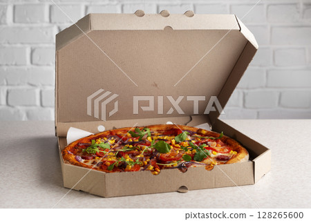 Large Pizza in open carton box on kitchen table closeup view 128265600