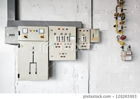 Electrical Control Panels Mounted on Textured Concrete Wall. 128265983
