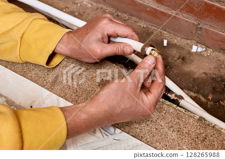 Installation process shows technician fitting compression ring to composite tubing before connecting water supply lines using compression fitting for plumbing work. 128265988