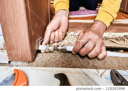 Plumber aligns stub of compression coupling inside composite tubing to enable correct positioning before ring is tightened around joint. 128265996