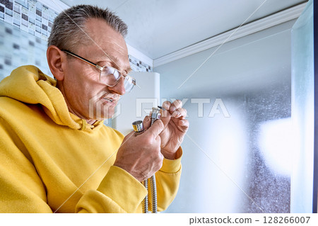 Plumber places sealing ring inside metal nut on flexible hose, ensuring leak-free joint before attaching shower hose in enclosed shower area. 128266007