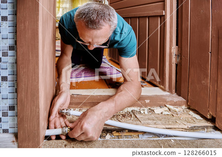 Plumber aligns multilayer pipe sections and installs compression coupling to repair water line damaged by freeze-induced crack during winter. Plumber aligns multilayer pipe sections and installs compression coupling to repair water line damaged by freeze-induced crack during winter. 128266015