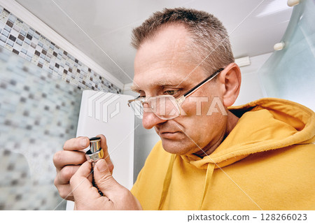 Worker inserts rubber gasket into hose nut, preparing shower hose connection to prevent water leaks during installation in shower cabin. Worker inserts rubber gasket into hose nut, preparing shower hose connection to prevent water leaks during installation in shower cabin. 128266023